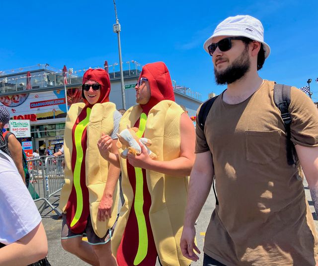 A couple of men in hot dog suits walk the Coney Island boardwalk after the annual Fourth of July hot dog eating contest.